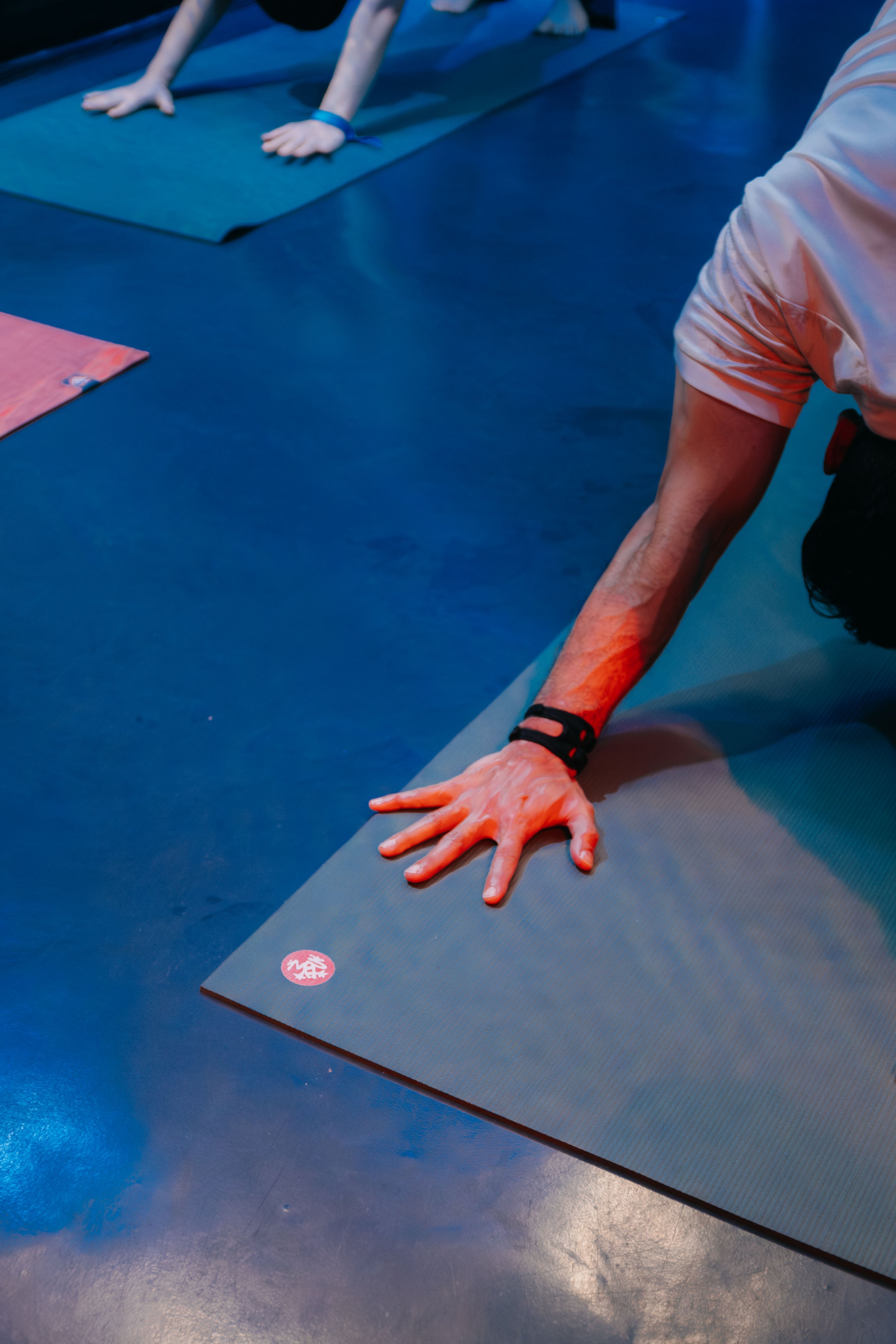 A practitioner’s hand grounded on a Manduka mat